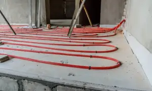 Instalacja ogrzewania podłogowego z czerwonych rurek na płycie, przygotowana pod wylewkę. Dobry styropian na podłogę to klucz do efektywności.