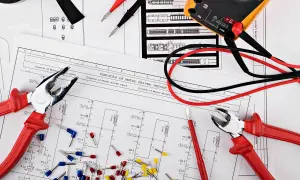 Schemat elektryczny z narzędziami: kombinerki, miernik i złączki. Widać symbol kondensatora.