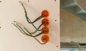 Instalacja elektryczna w trakcie budowy. Widoczne puszki instalacyjne i kolorowe przewody.