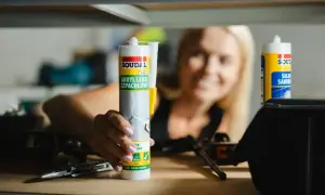 Kobieta trzyma tubkę akrylu lekkiego szpachlowego Soudal. Akryl to wszechstronny materiał budowlany.