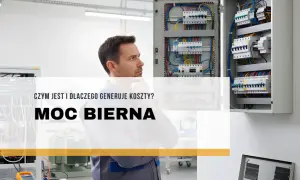 Elektryk zastanawia się nad zagadnieniem mocy biernej, która generuje koszty. Widoczne rozdzielnice elektryczne.