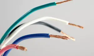 Pięć przewodów elektrycznych w różnych kolorach: zielonym, białym, czarnym, niebieskim i różowym, ukazujących swoje miedziane żyły. Różnorodność kolorów faz ułatwia identyfikację.