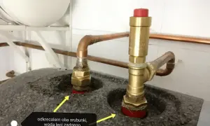 Dwa mosiężne śrubunki z miedzianymi rurkami, jeden z zaworem bezpieczeństwa. Woda leci, powietrza brak.