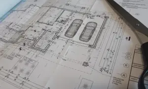 Projekt architektoniczno budowlany domu z garażem, nożyczki przecinają plany.
