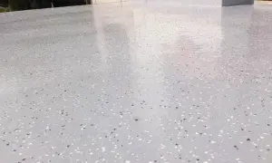 Nowoczesny kamienny dywan koszt 1m2. Jasnoszara powierzchnia z drobnymi, kolorowymi płatkami, idealna na taras lub balkon.