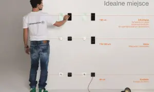 Mężczyzna pokazuje idealne miejsca na montaż włączników światła: 150 cm dla informacji, 110-120 cm dla akcji, 30 cm dla zasilania.
