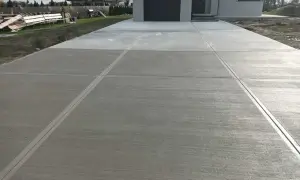 Nowy podjazd z beton stemplowany, z wyraźnymi liniami podziału, prowadzi do nowoczesnego domu.
