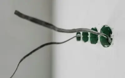 Przewody elektryczne wychodzące z zielonych puszek instalacyjnych, gotowe do podłączenia uziemienia w gniazdku.