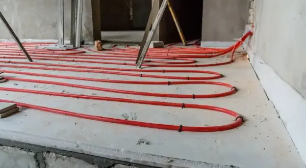 Instalacja ogrzewania podłogowego z czerwonych rurek na płycie, przygotowana pod wylewkę. Dobry styropian na podłogę to klucz do efektywności.
