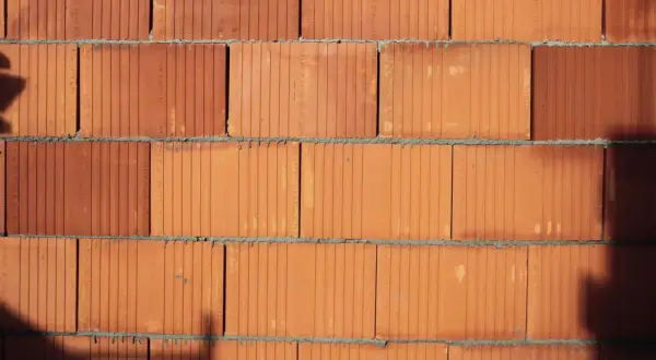 Ściana z pustaków ceramicznych. Widoczne są pionowe i poziome fugi. Pustak ceramiczny wymiary są standardowe, idealne do budowy.