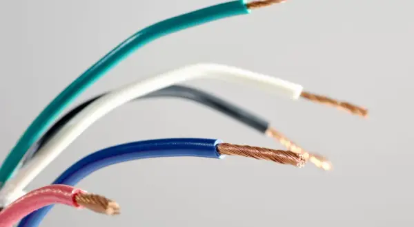 Pięć przewodów elektrycznych w różnych kolorach: zielonym, białym, czarnym, niebieskim i różowym, ukazujących swoje miedziane żyły. Różnorodność kolorów faz ułatwia identyfikację.
