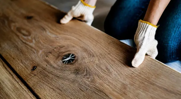 Ręce w rękawiczkach układają drewniane deski. Zastanawiasz się, jakie panele podłogowe wybrać? Ten naturalny wygląd może być inspiracją.