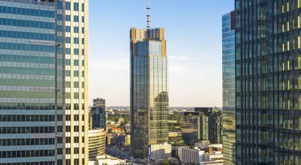 Warszawski wieżowiec, najwyższy budynek w Polsce, góruje nad miastem, otoczony innymi nowoczesnymi drapaczami chmur.