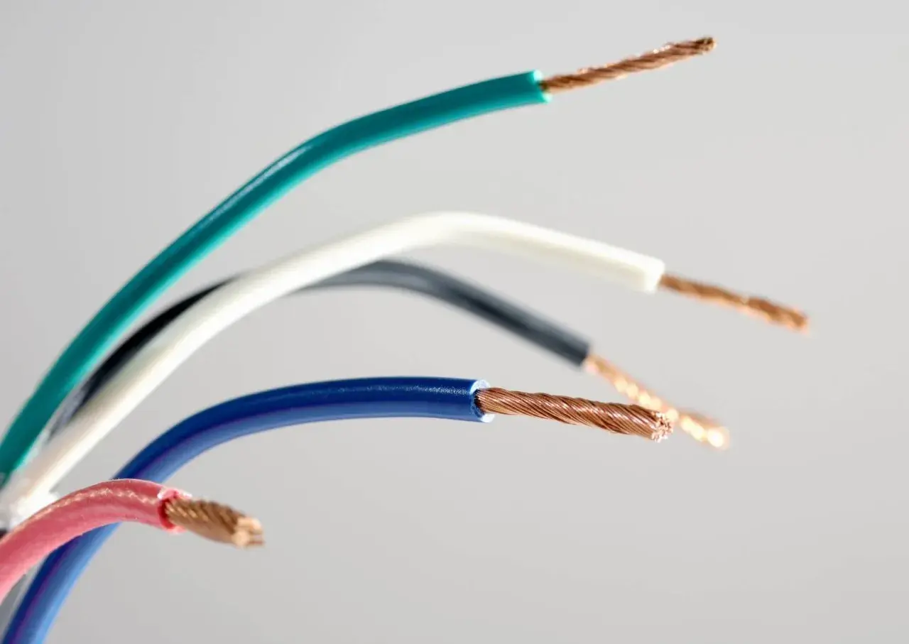 Pięć przewodów elektrycznych w różnych kolorach: zielonym, białym, czarnym, niebieskim i różowym, ukazujących swoje miedziane żyły. Różnorodność kolorów faz ułatwia identyfikację.