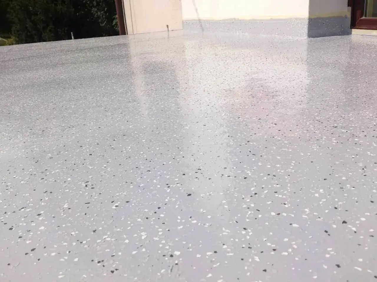 Nowoczesny kamienny dywan koszt 1m2. Jasnoszara powierzchnia z drobnymi, kolorowymi płatkami, idealna na taras lub balkon.