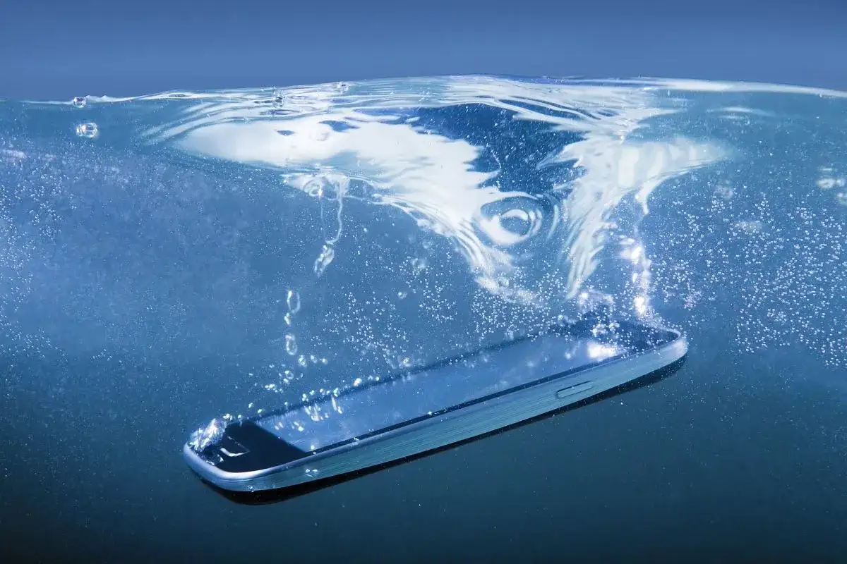 Smartfon z certyfikatem IP67 zanurza się w wodzie, tworząc wir i bąbelki.