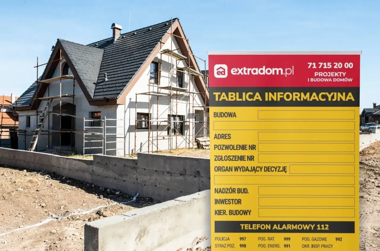 Tablica informacyjna budowy domu w trakcie prac, z widocznymi rusztowaniami i fundamentami. Na tablicy dane o inwestycji.