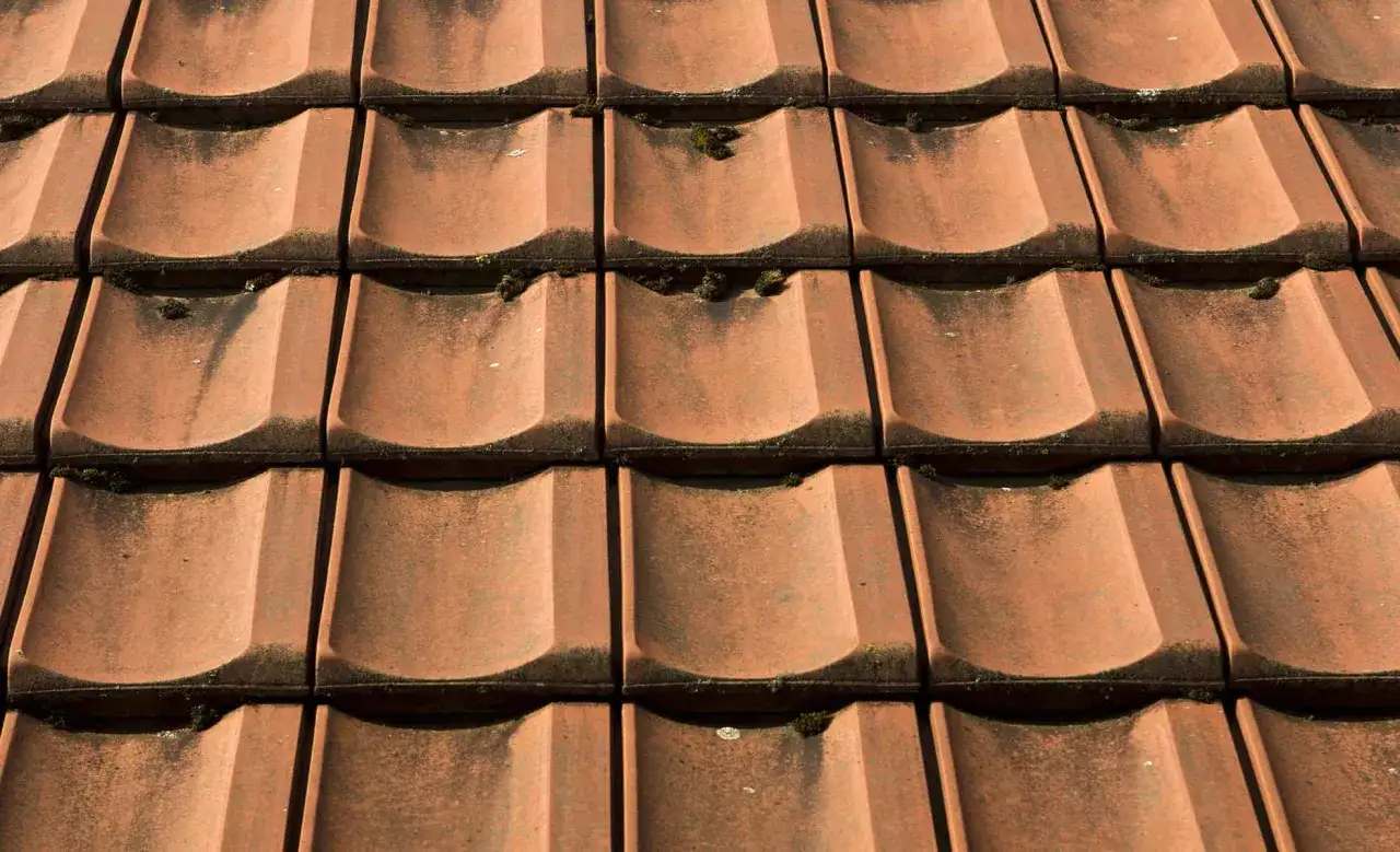 Czerwona dachówka ceramiczna, lekko porośnięta mchem. Sprawdź aktualną dachówka ceramiczna cena za m2.