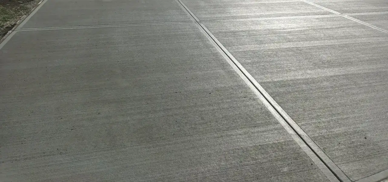 Szara nawierzchnia z widocznymi liniami fug, przypominająca beton stemplowany.