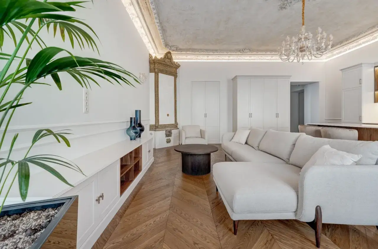 Elegancki salon z kanapą, ozdobnym piecem i podłogą w jodełkę francuską.