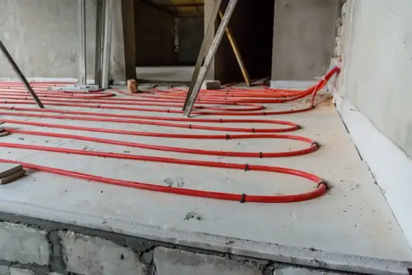 Instalacja ogrzewania podłogowego z czerwonych rurek na płycie, przygotowana pod wylewkę. Dobry styropian na podłogę to klucz do efektywności.