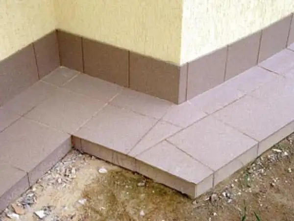Wykonana opaska wokół domu z płytek ceramicznych, chroniąca fundament przed wilgocią.