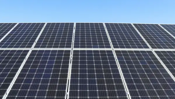 Duża instalacja PV pod błękitnym niebem. Panele słoneczne tworzą równą, ciemną powierzchnię, gotową do produkcji czystej energii.