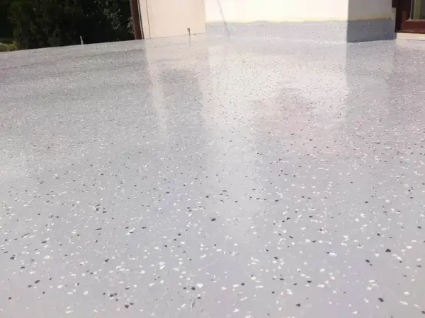 Nowoczesny kamienny dywan koszt 1m2. Jasnoszara powierzchnia z drobnymi, kolorowymi płatkami, idealna na taras lub balkon.
